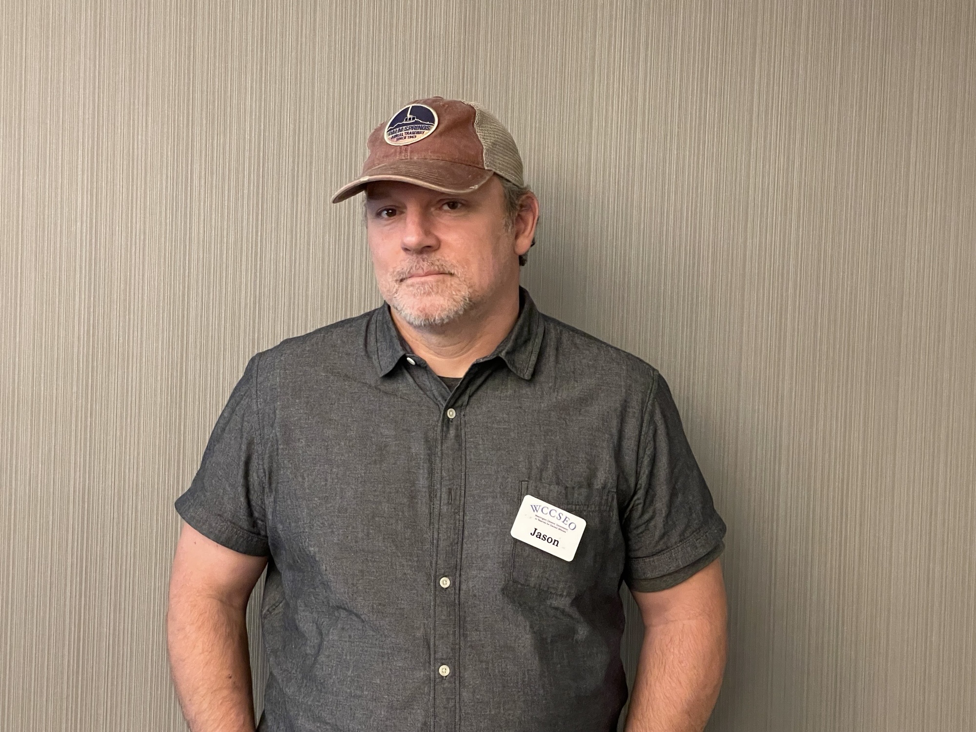 Jason, man wearing a ball cap and a gray button up shirt